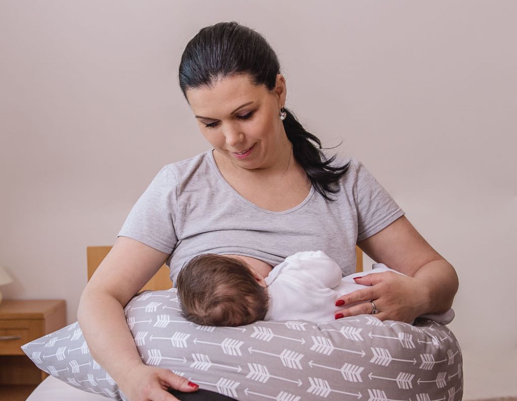 New mom comfortably nursing baby with a soft C-section-friendly nursing pillow