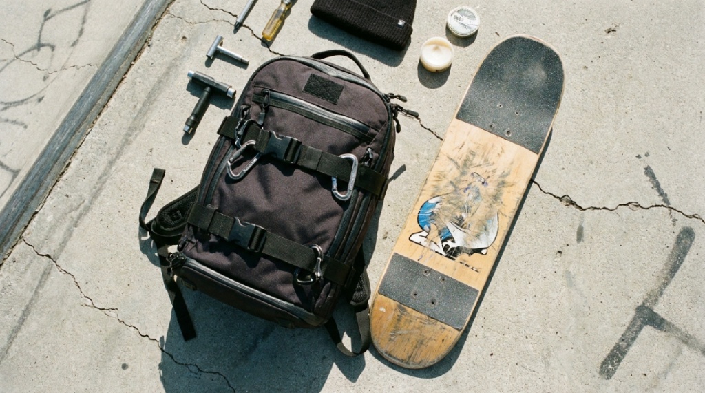 Skateboarder carrying a durable backpack on a sunny Florida sidewalk.
