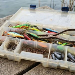 Fishing lures, hooks, and tools arranged in a tackle box